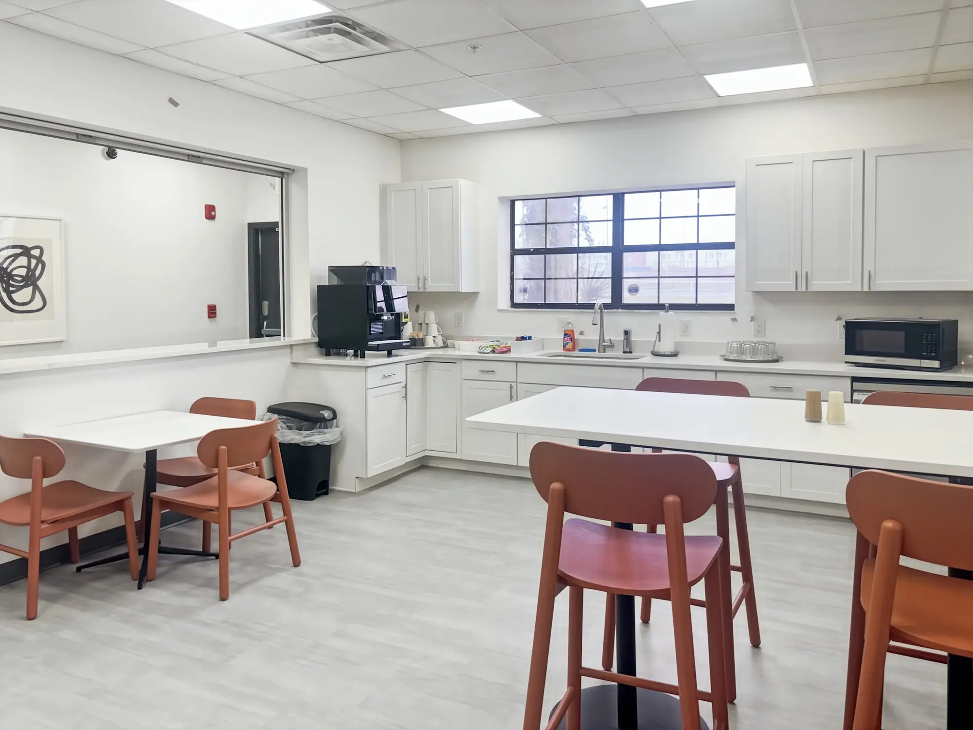 A break room with a kitchenette, coffee machine and orange bar stools
