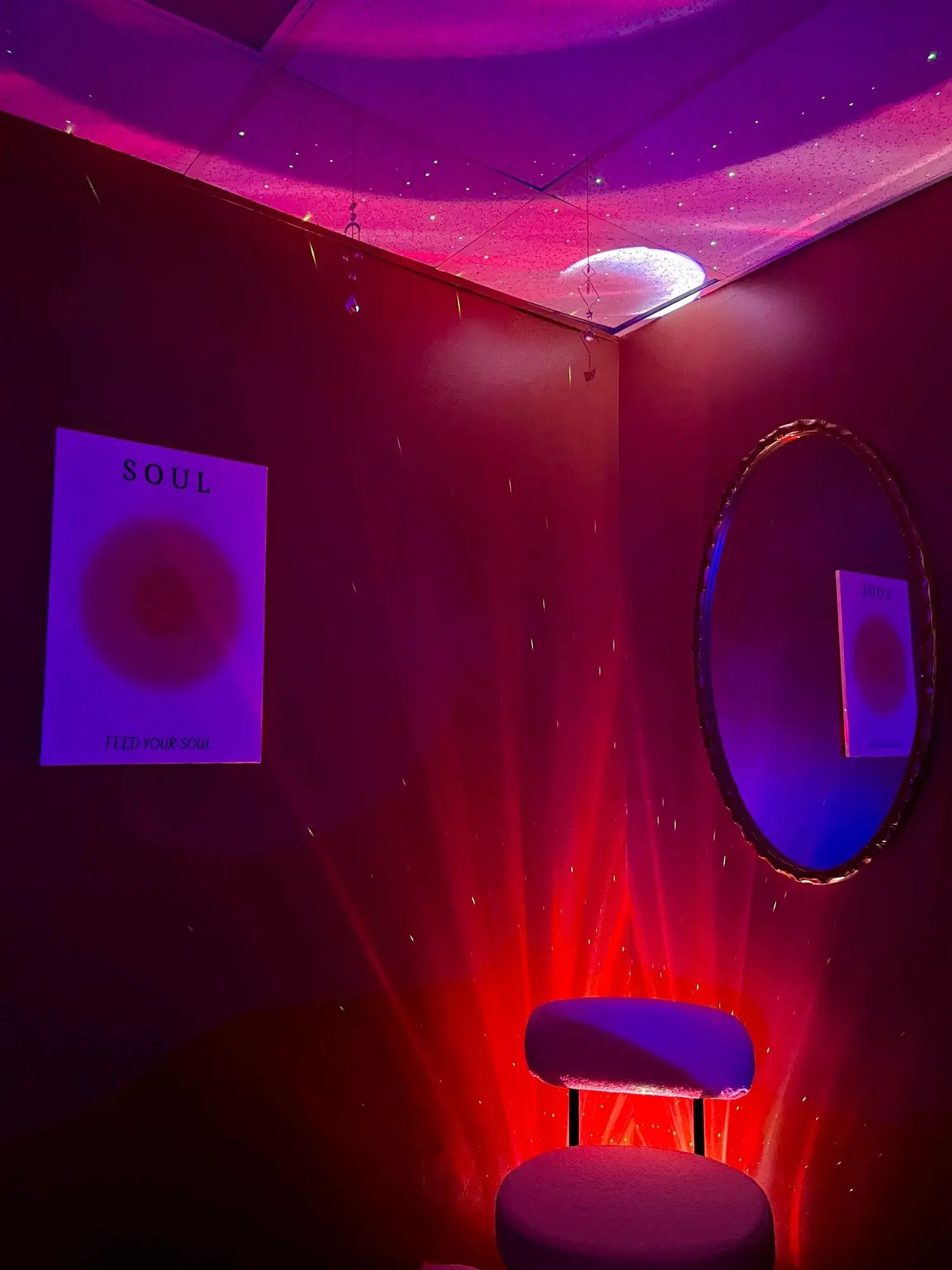 The Chakra Chamber, washed in purple and red light, with a round mirror and a velvet chair