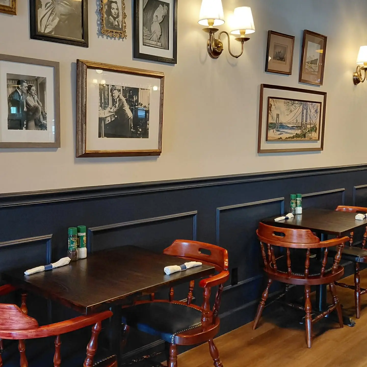 Tables for two under brass wall sconces and framed vintage photos