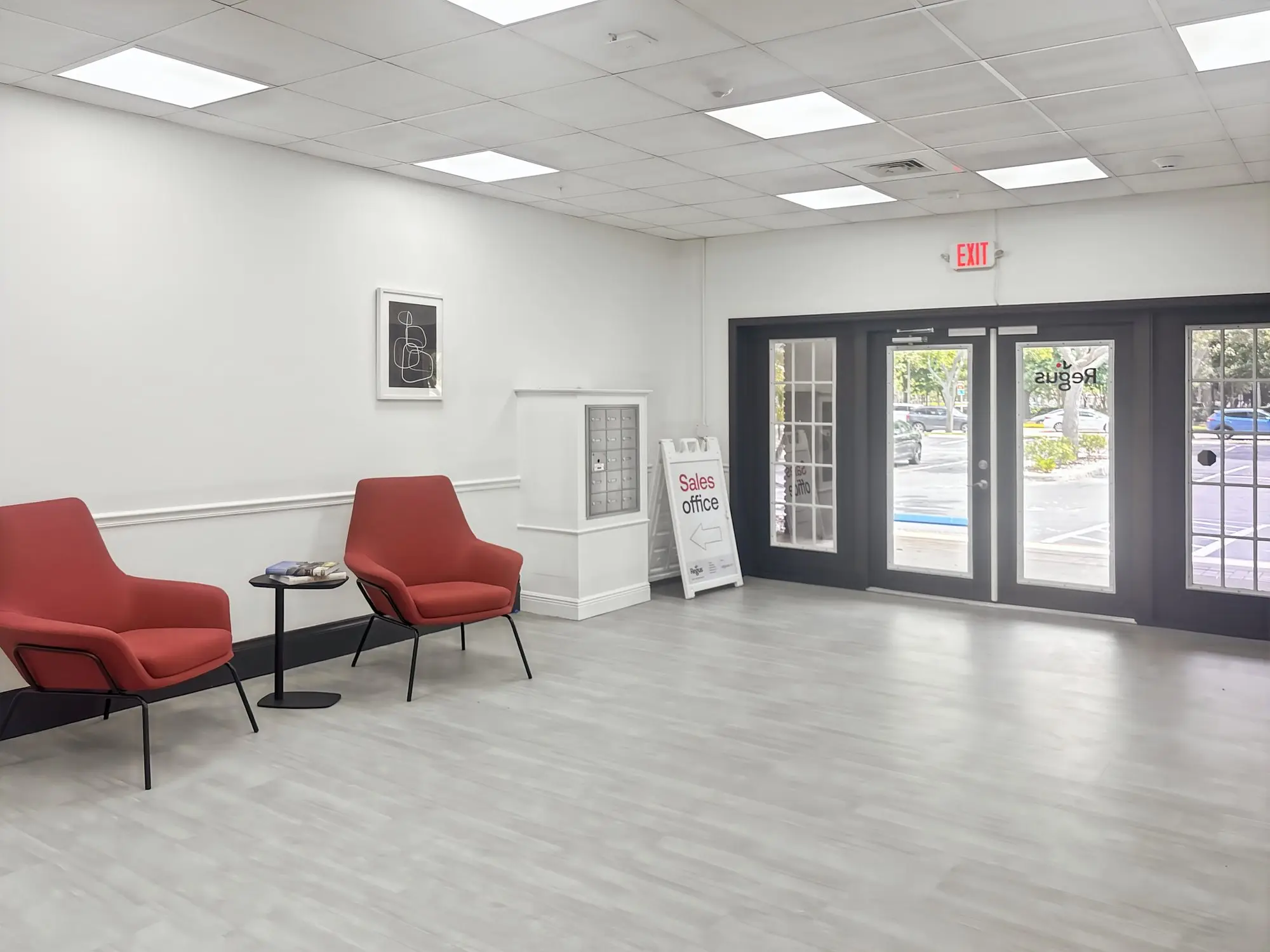 Two red lounge chairs beside the glass entry doors