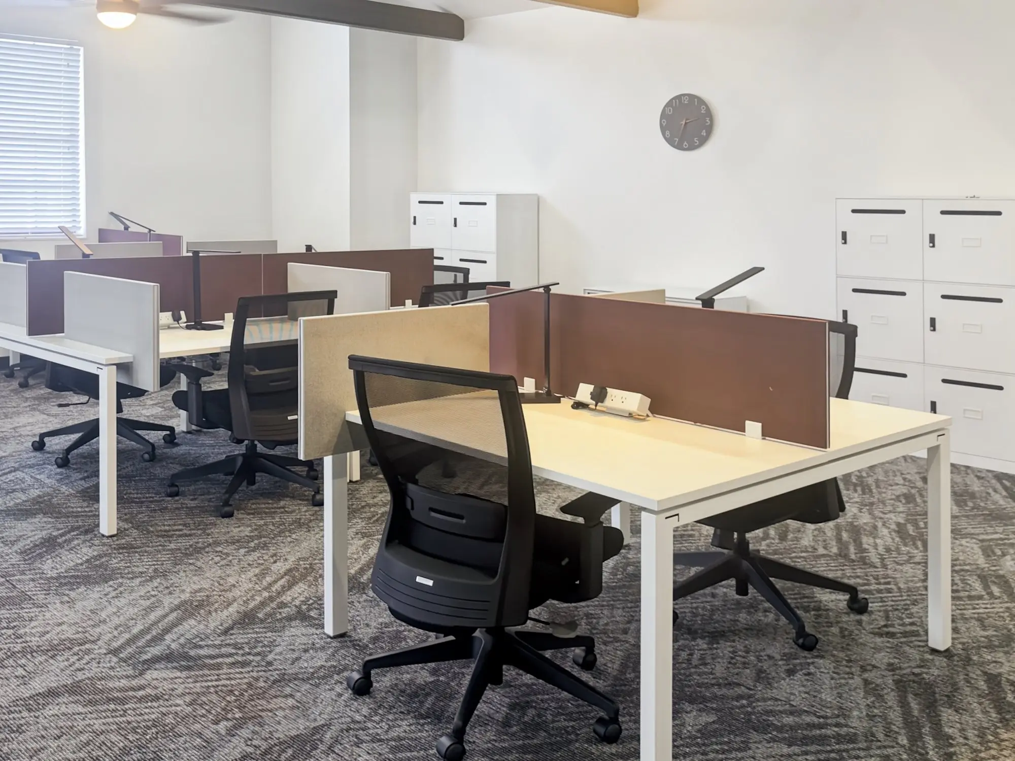 A team office with rows of desks, rolling chairs and storage lockers